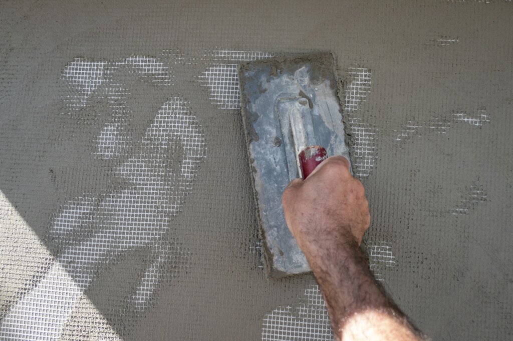 a trowel applying cement on a wall
